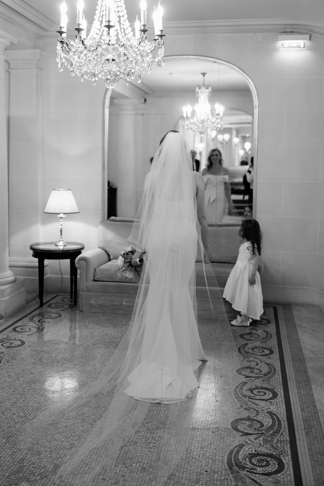 Bride walking through Hôtel Plaza Athénée with a flower girl before the ceremony